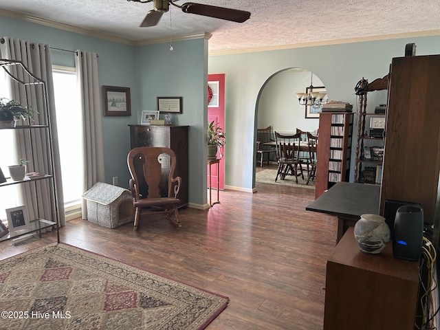 sitting room with ornamental molding, arched walkways, a textured ceiling, and wood finished floors