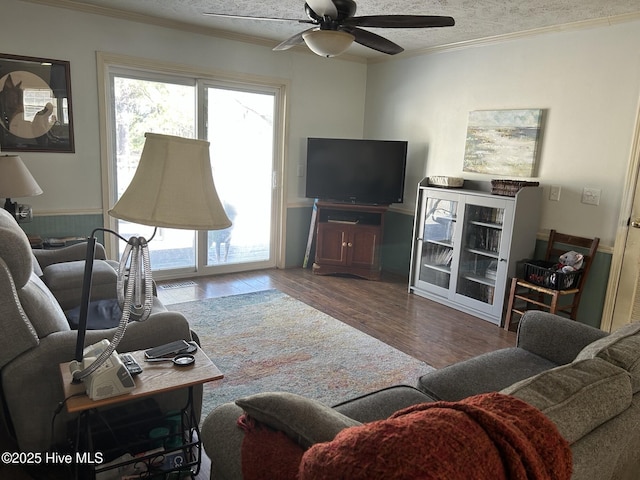 living area with ceiling fan, a textured ceiling, wood finished floors, and crown molding