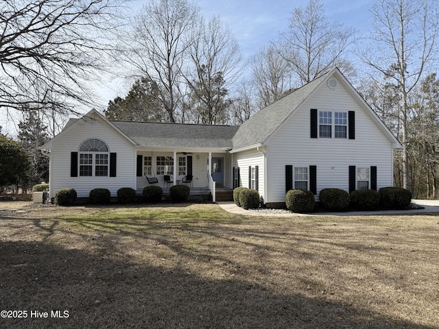 view of front facade featuring a shingled roof, a porch, and a front yard