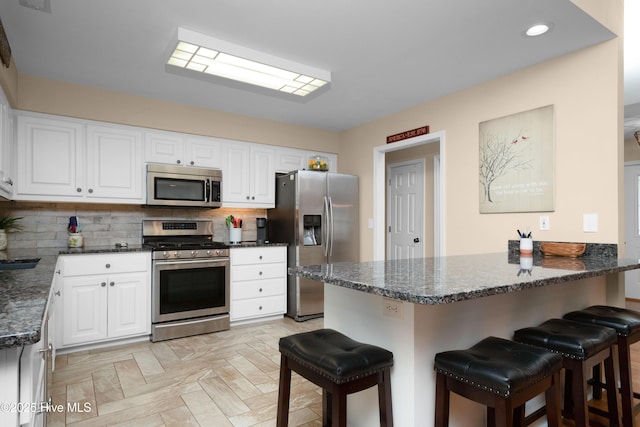 kitchen with a peninsula, appliances with stainless steel finishes, a kitchen breakfast bar, and backsplash