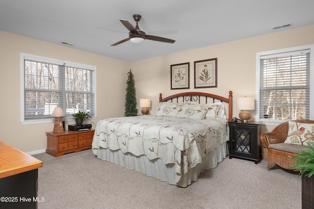 carpeted bedroom featuring ceiling fan, multiple windows, and visible vents