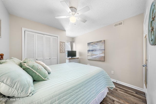 bedroom with baseboards, visible vents, dark wood finished floors, a textured ceiling, and a closet