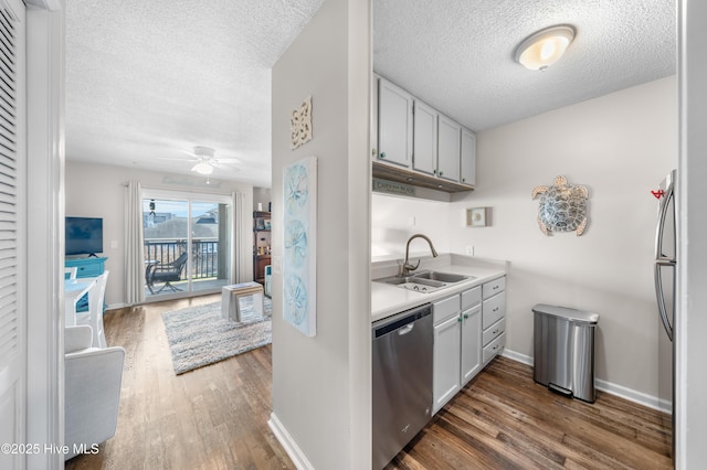 kitchen featuring dark wood-style floors, light countertops, a sink, dishwasher, and baseboards