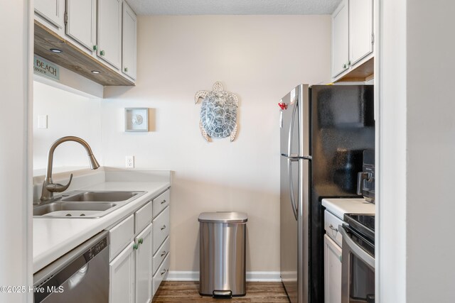 kitchen with white cabinets, stainless steel appliances, light countertops, and a sink