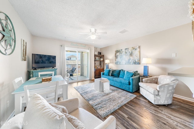 living area with ceiling fan, dark wood-style flooring, and a textured ceiling