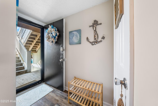 doorway featuring a textured ceiling, a healthy amount of sunlight, dark wood finished floors, and baseboards