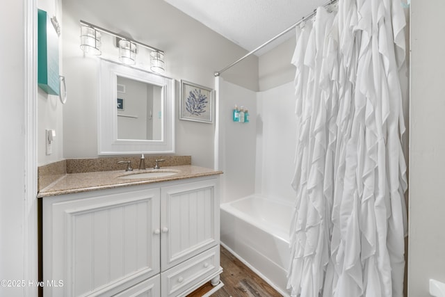 bathroom with a textured ceiling, wood finished floors, vanity, and shower / tub combo with curtain