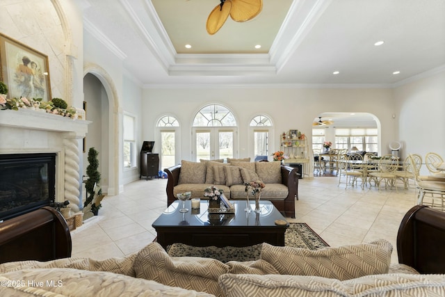 living room featuring a wealth of natural light, light tile patterned flooring, a glass covered fireplace, and a ceiling fan