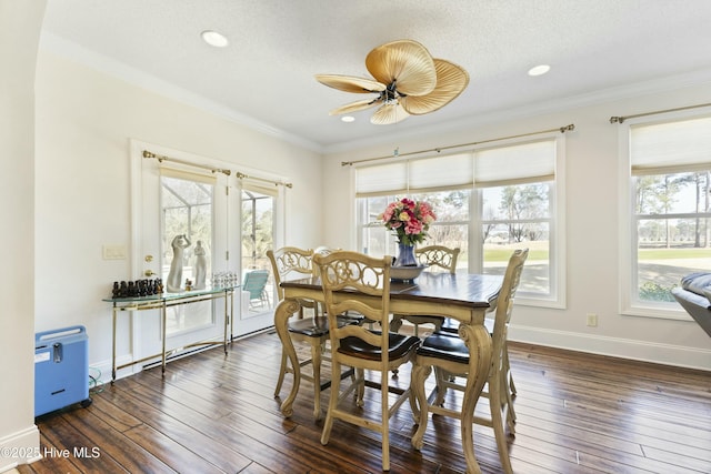 dining area featuring a textured ceiling, a ceiling fan, baseboards, wood-type flooring, and crown molding