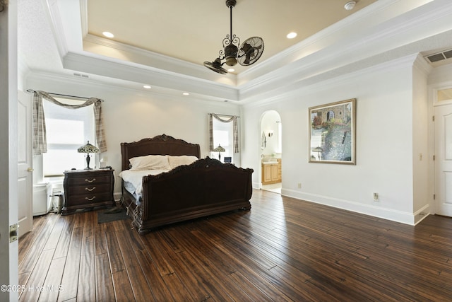 bedroom featuring arched walkways, a tray ceiling, dark wood-type flooring, and visible vents