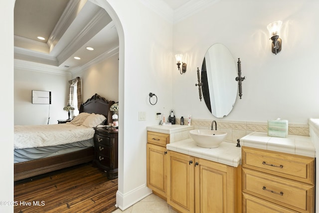 full bath featuring ensuite bathroom, recessed lighting, vanity, ornamental molding, and a raised ceiling