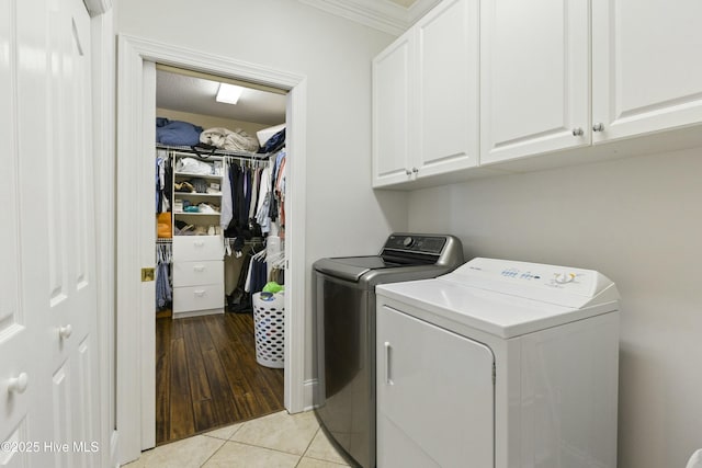 clothes washing area featuring ornamental molding, cabinet space, independent washer and dryer, and light tile patterned flooring