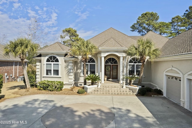 view of front of house featuring a garage, concrete driveway, roof with shingles, and stucco siding