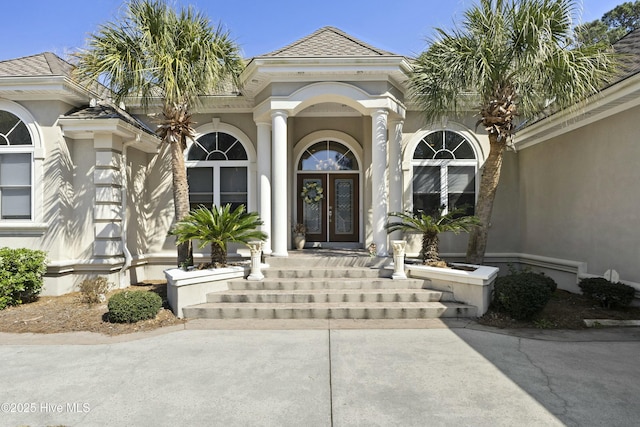 property entrance featuring a shingled roof, french doors, and stucco siding