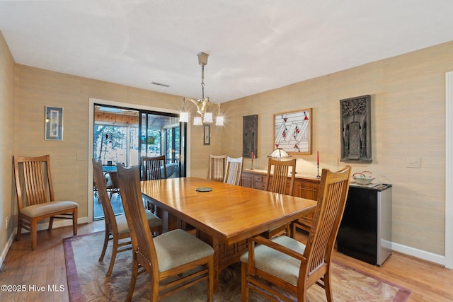 dining area featuring wallpapered walls, light wood finished floors, an inviting chandelier, and baseboards