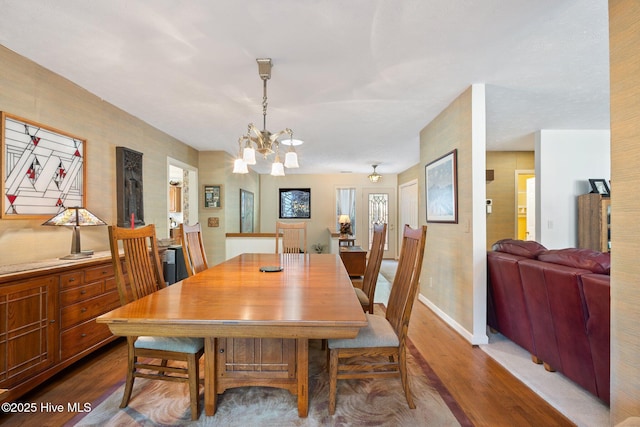 dining area featuring baseboards, wood finished floors, and an inviting chandelier