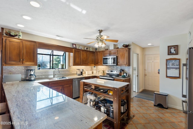 kitchen with appliances with stainless steel finishes, brown cabinets, a sink, and tasteful backsplash