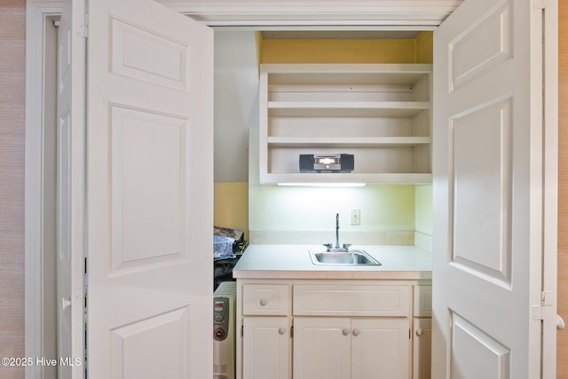 kitchen featuring open shelves, light countertops, and a sink