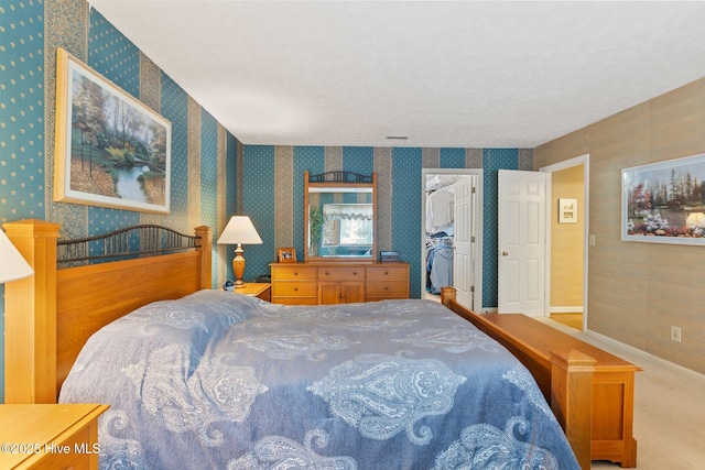 bedroom with a spacious closet and wallpapered walls