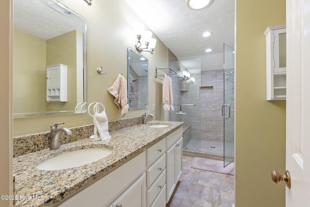 bathroom featuring double vanity, a shower stall, a textured ceiling, and a sink