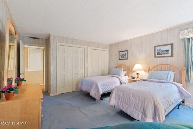 carpeted bedroom with multiple closets, visible vents, crown molding, and baseboards