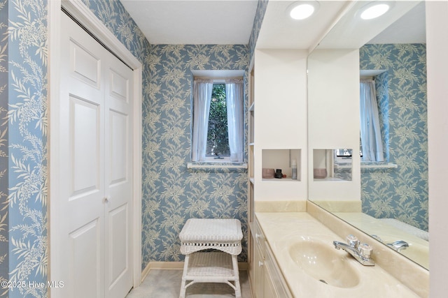 bathroom with wallpapered walls, a closet, and vanity