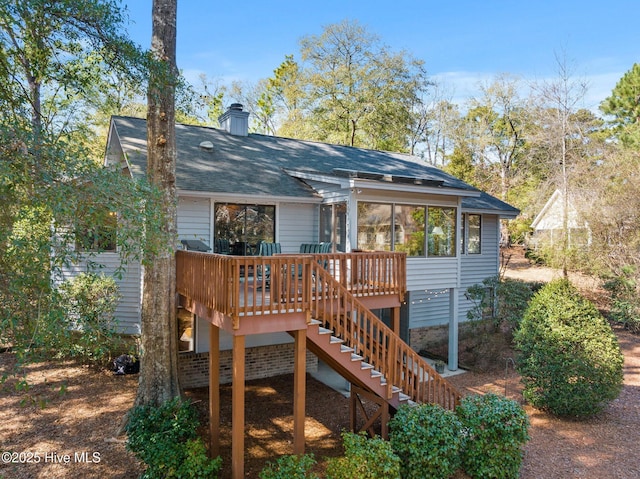 rear view of property with a deck, stairway, a chimney, and a sunroom