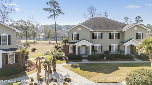 view of front facade featuring roof with shingles, brick siding, and a front lawn