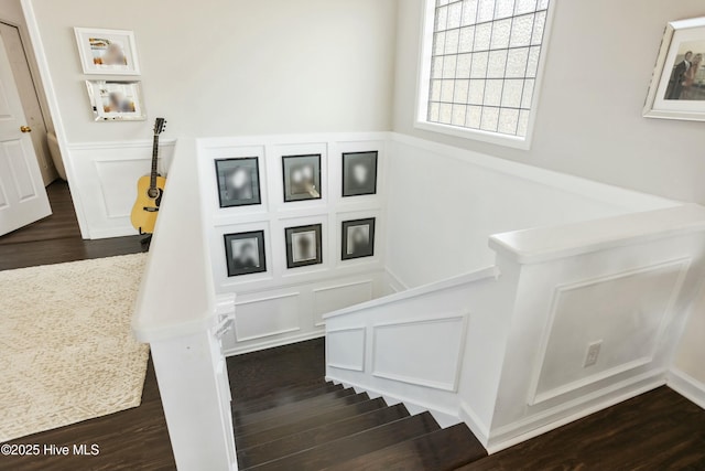 staircase featuring wainscoting, wood finished floors, and a decorative wall