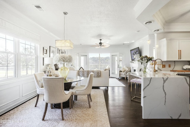 dining space with dark wood-type flooring, a wealth of natural light, visible vents, and ornamental molding