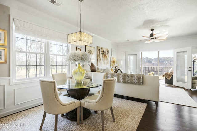 dining room featuring a textured ceiling, wood finished floors, visible vents, and a healthy amount of sunlight