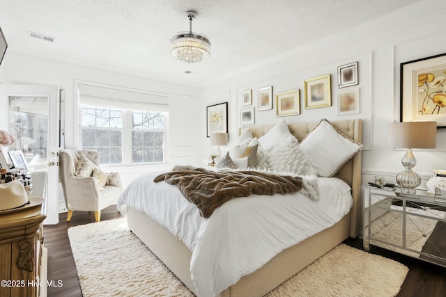 bedroom with a textured ceiling, visible vents, and wood finished floors