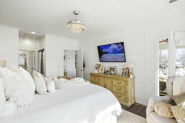 bedroom with attic access, visible vents, dark wood-style floors, ornamental molding, and a decorative wall