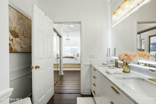 full bath featuring double vanity, ensuite bath, a sink, and wood finished floors