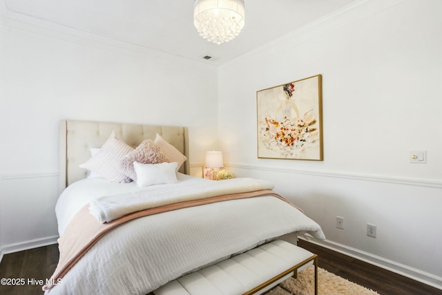 bedroom with ornamental molding, baseboards, an inviting chandelier, and wood finished floors