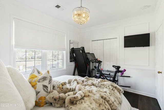 bedroom featuring a chandelier, dark wood-style flooring, visible vents, a closet, and crown molding