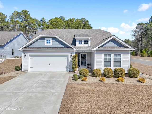 view of front facade with driveway, a shingled roof, and a garage