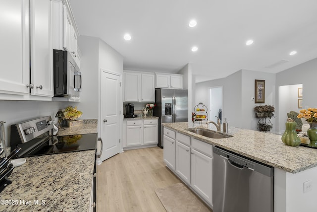 kitchen featuring stainless steel appliances, light wood-style floors, white cabinetry, and a sink