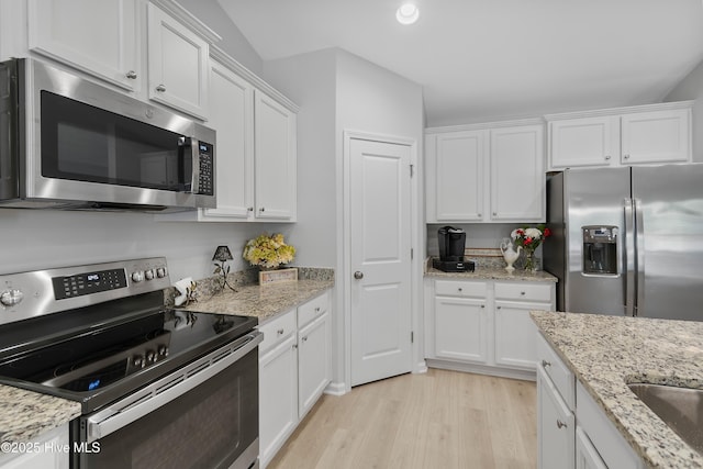 kitchen with light wood-type flooring, light stone countertops, white cabinetry, and stainless steel appliances