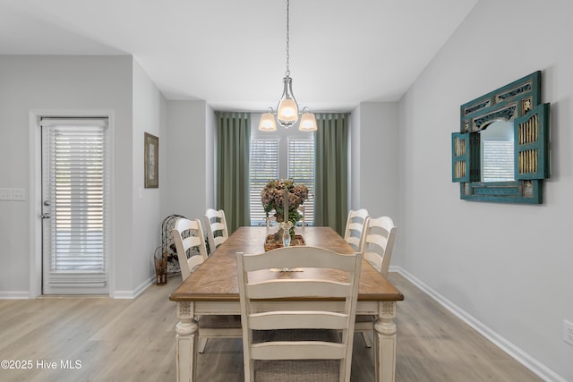 dining space featuring baseboards, an inviting chandelier, and light wood-style floors