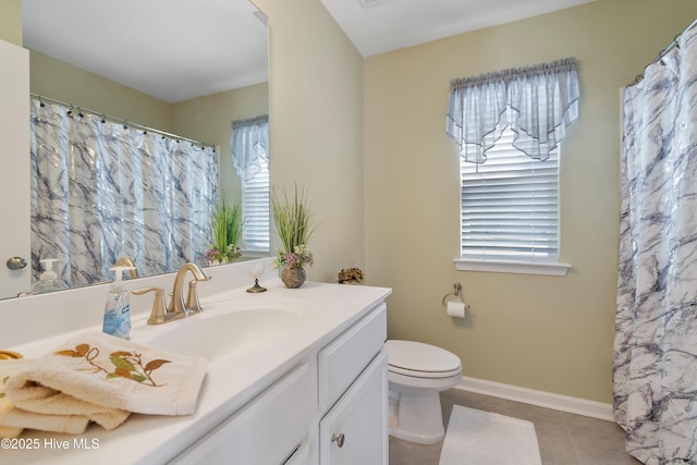 bathroom with tile patterned flooring, baseboards, vanity, and toilet