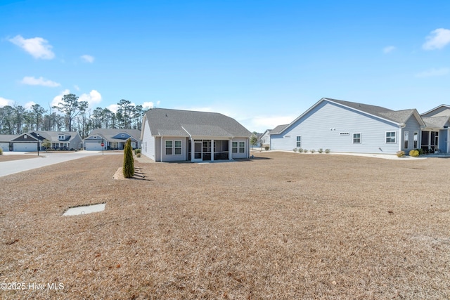 back of house featuring a sunroom, a residential view, and a lawn