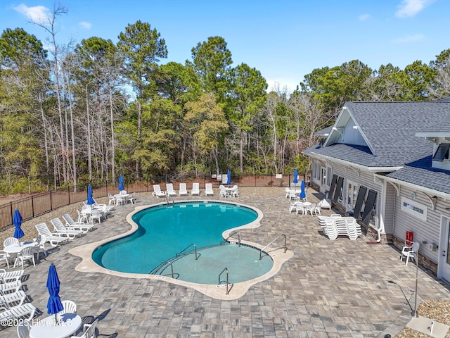 pool with a patio area and fence