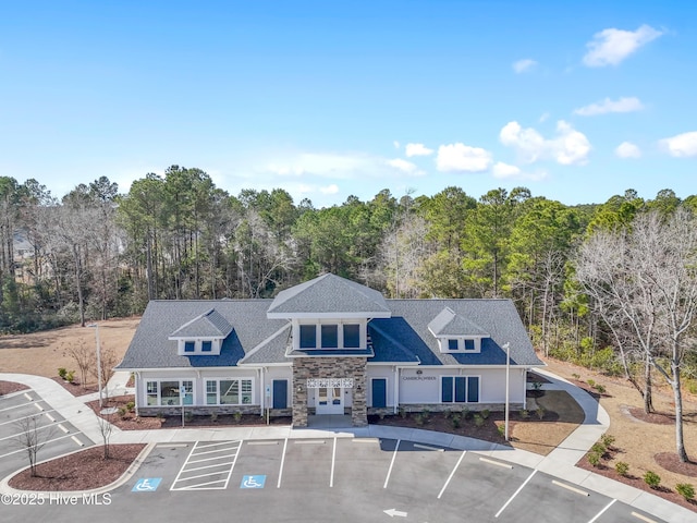 view of property featuring uncovered parking and a view of trees