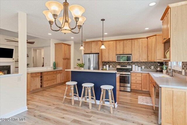122 Smathers Dr, West End, NC 27376 - kitchen featuring appliances with stainless steel finishes, a sink, a kitchen island, a kitchen bar, and light wood-style flooring