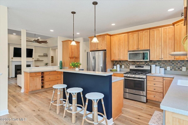 122 Smathers Dr, West End, NC 27376 - kitchen featuring appliances with stainless steel finishes, a center island, light wood finished floors, backsplash, and light countertops