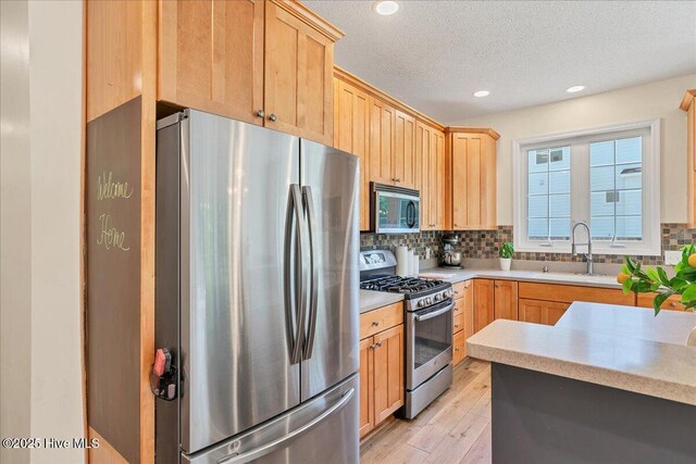 122 Smathers Dr, West End, NC 27376 - kitchen featuring stainless steel appliances, a sink, light brown cabinets, light wood-type flooring, and a textured ceiling