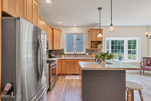 122 Smathers Dr, West End, NC 27376 - kitchen featuring appliances with stainless steel finishes, a textured ceiling, backsplash, light countertops, and light wood-type flooring