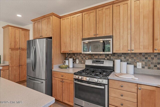 122 Smathers Dr, West End, NC 27376 - kitchen featuring appliances with stainless steel finishes, light countertops, decorative backsplash, a textured ceiling, and recessed lighting