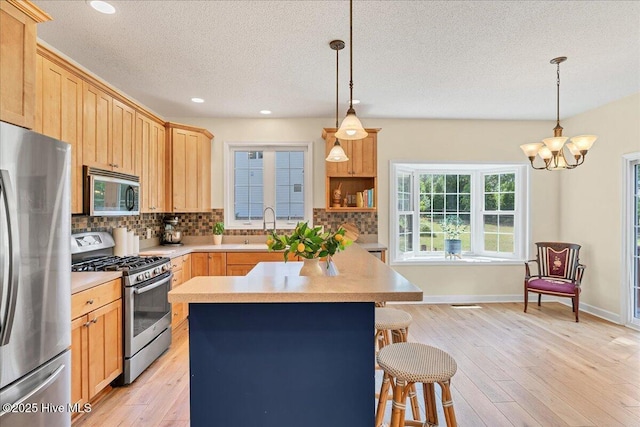 122 Smathers Dr, West End, NC 27376 - kitchen featuring stainless steel appliances, light brown cabinetry, tasteful backsplash, a breakfast bar, and a textured ceiling